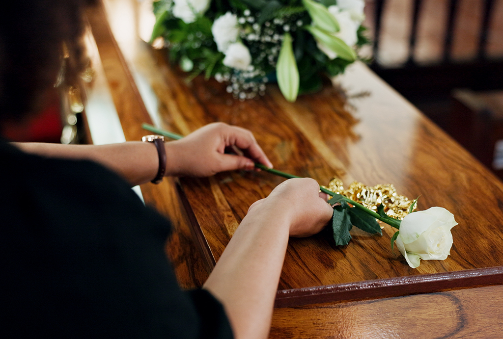 woman placing rose at funeral