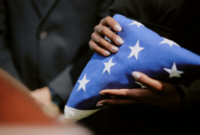 woman holding folded American flag during veteran funeral ceremony
