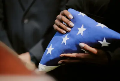 woman holding folded American flag during veteran funeral ceremony